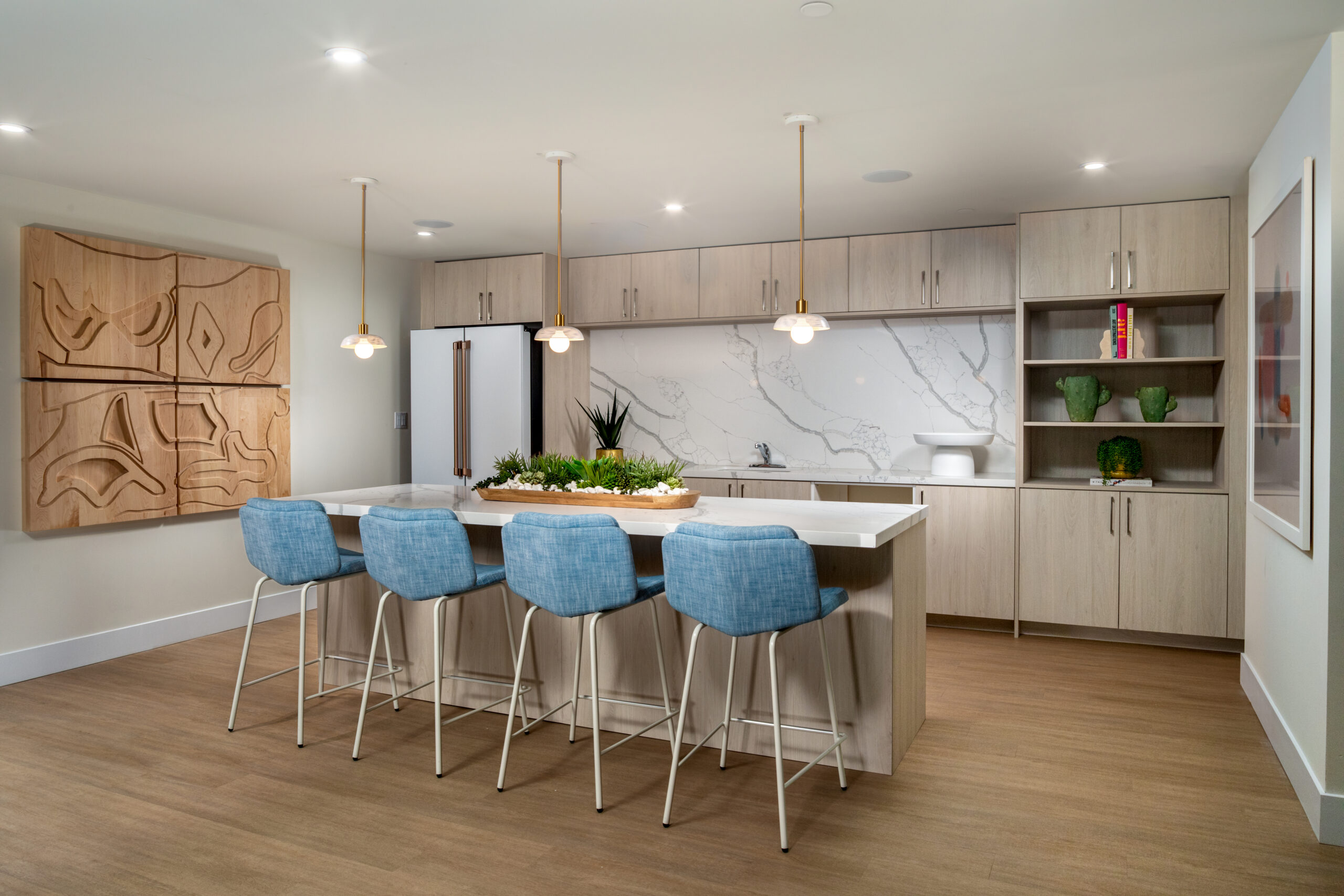 A resident kitchen with an island and chairs with light cabintery.
