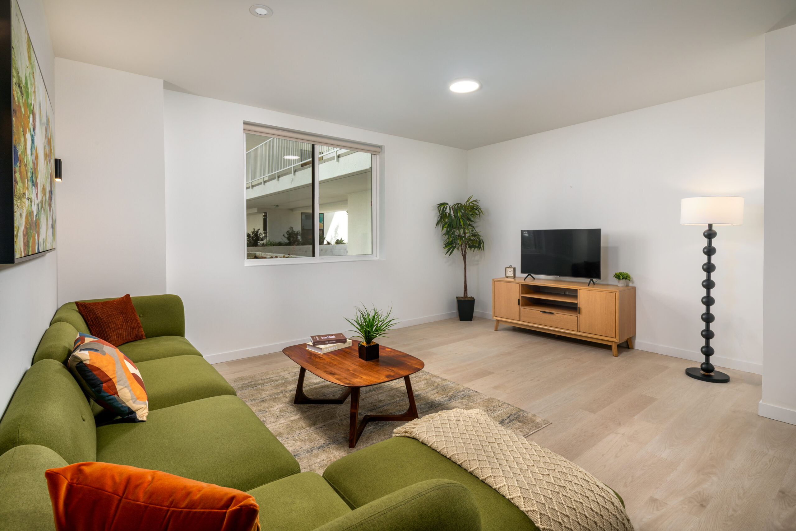 A spacious living room with a green couch, coffee table, and TV.