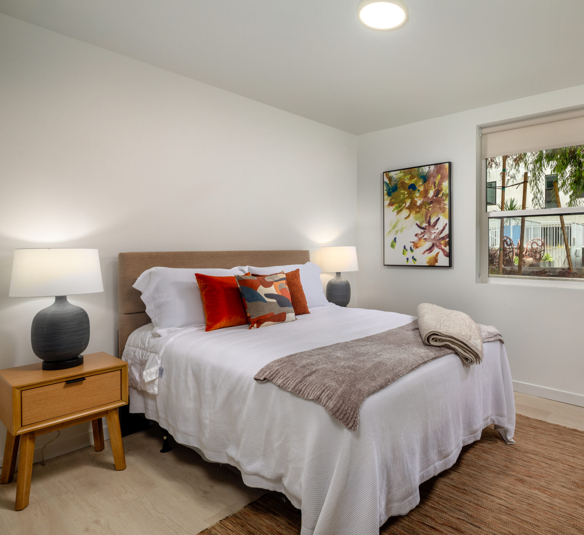 A bedroom with a bed, nightstand, and window.