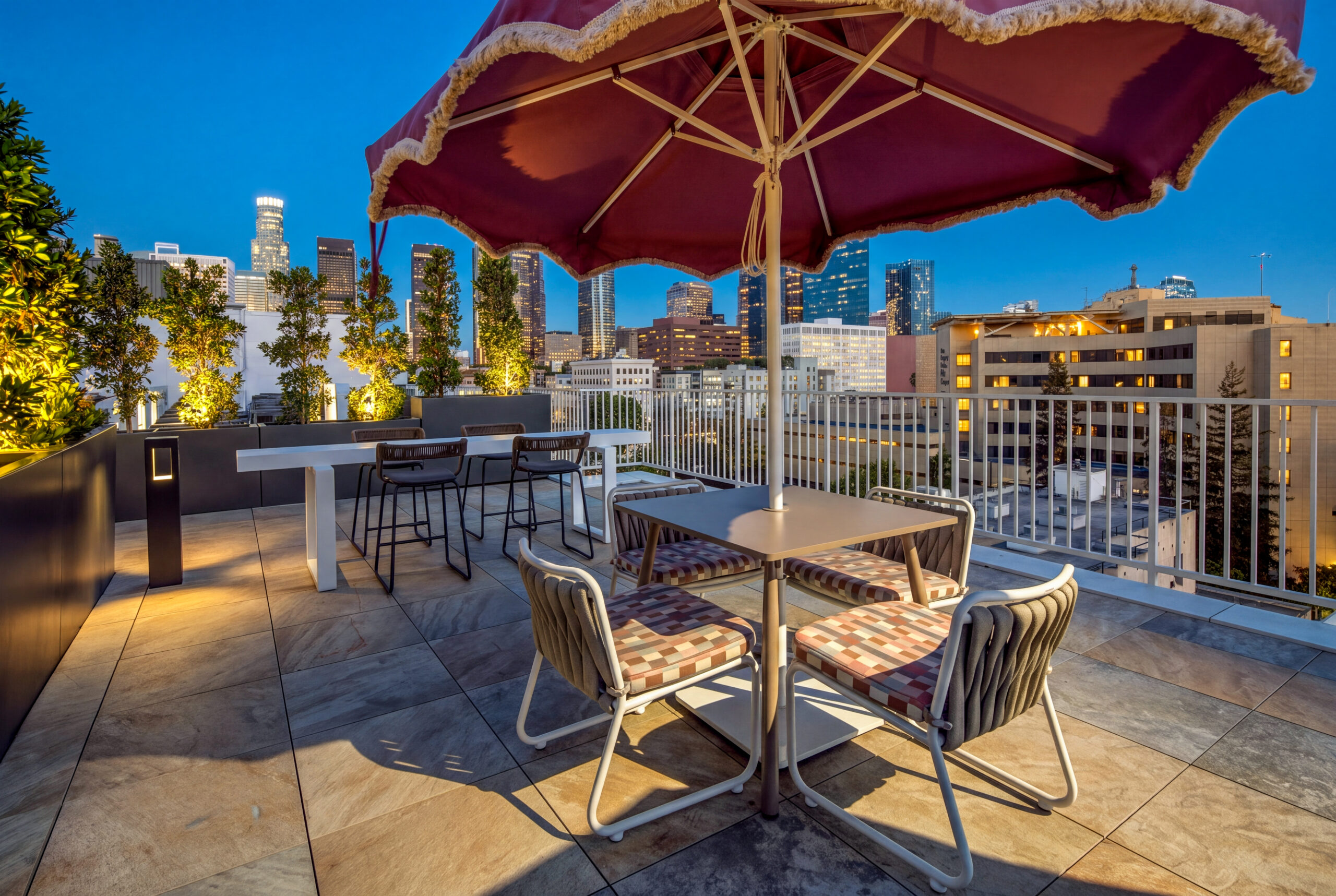 A rooftop patio with chairs and a view of Downtown Los Angeles.